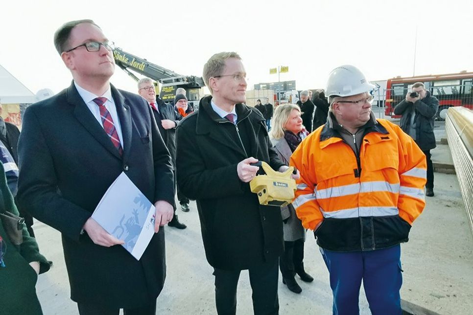 Ministerpräsident Daniel Günther hat mit einer Funk-Fernbedienung die erste Bohle in den Grund gerammt, beobachtet von Bürgermeister Jan Lindenau (li.), Guido Kaschel, Leiter Lübeck Port Authority (LPA), und Bausenatorin Joanna Hagen.