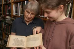 Gyde Wiese und Vivien Sobol, die neue FSJ-Teilnehmerin im Haus der Natur - Cismar, freuen sich über den historischen Bibliotheks-Zuwachs.
