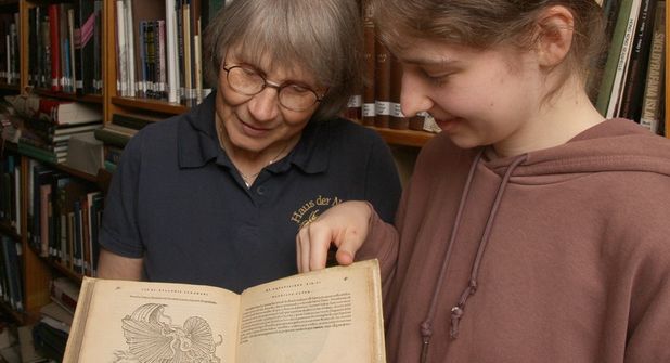 Gyde Wiese und Vivien Sobol, die neue FSJ-Teilnehmerin im Haus der Natur - Cismar, freuen sich über den historischen Bibliotheks-Zuwachs.