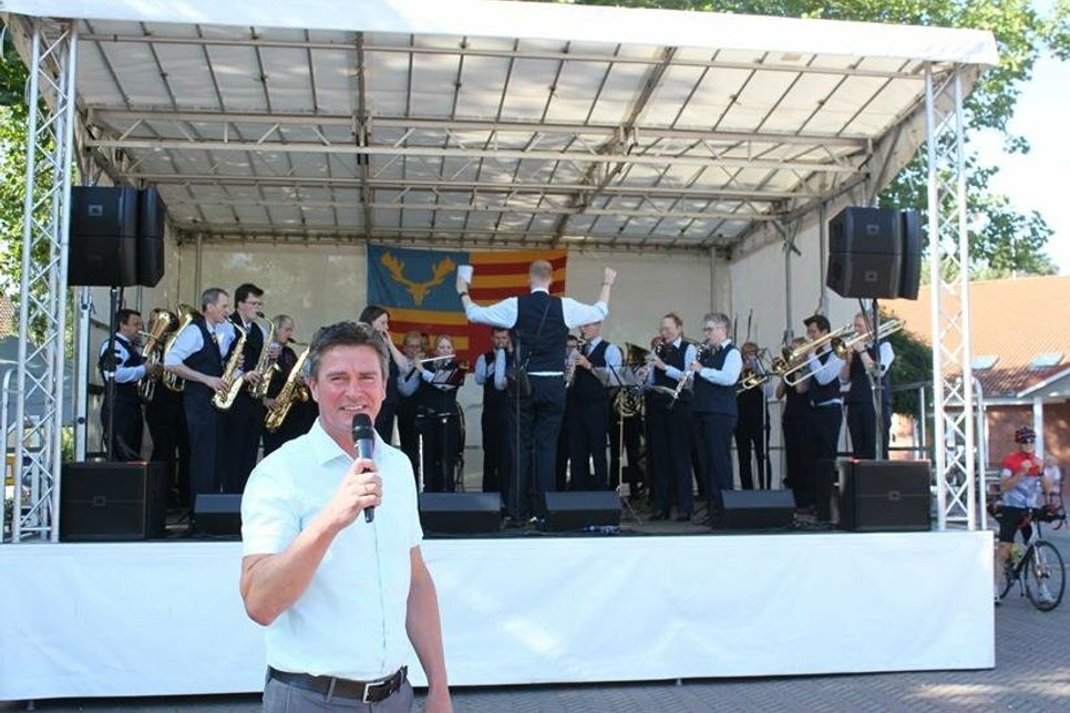 Bürgermeister Michael Robien bei der Eröffnung. Im Hintergrund auf der Bühne das Blasorchester Lensahn.