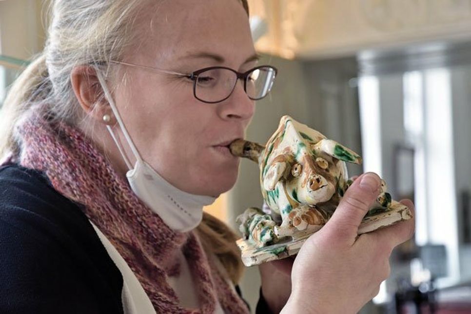 Museumsleiterin Julia Meyer demonstriert, wie das Feierabendstück aus Keramik, eine Spardose mit Schlitz, auch zum pfeifen benutzt werden konnte.
