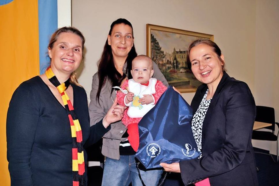 Bürgervorsteherin Anja Evers (li.) und Bürgermeisterin Hatice Kara überreichen das erste Begrüßungspaket für Neugeborene an Milena (fünf Monate) und ihre Mutter Stefanie. (Foto: René Kleinschmidt)
