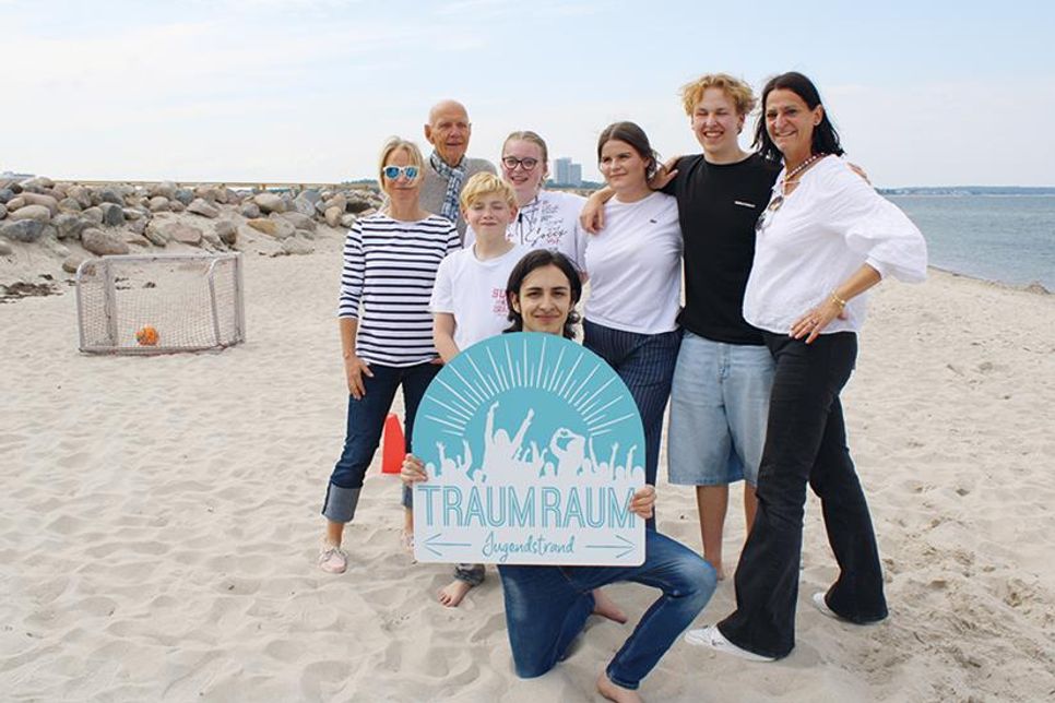 Lehrerin Sabine Jensen (links), Unterstützer Konrad Zinke und Marketingleiterin Silke Szymoniak (TSNT GmbH, rechts) freuen sich mit Torben Bahr, Leonie Timmermann, Paulina-Sophie Sikoudis, Maurice Cholewa und Gabriele Riccardo Giradi (mit Schild) über die Umsetzung des Jugendstrandes.