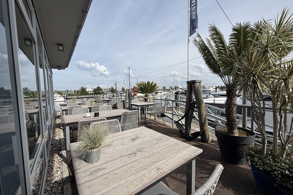 Die Terrassentische entstanden aus Holz alter Stege der Marina und erzählen ein Stück Hafengeschichte.