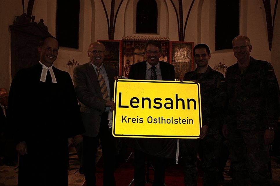 Ein Ortsschild der Gemeinde Lensahn geht mit in den Kosovo. Übergabe mit Pastor Kai Sagawe, Bürgervorsteher Wolfgang Schüller, Bürgermeister Klaus Winter, Hauptmann Nadir Attar und Oberstabsfeldwebel Klaus Behring.