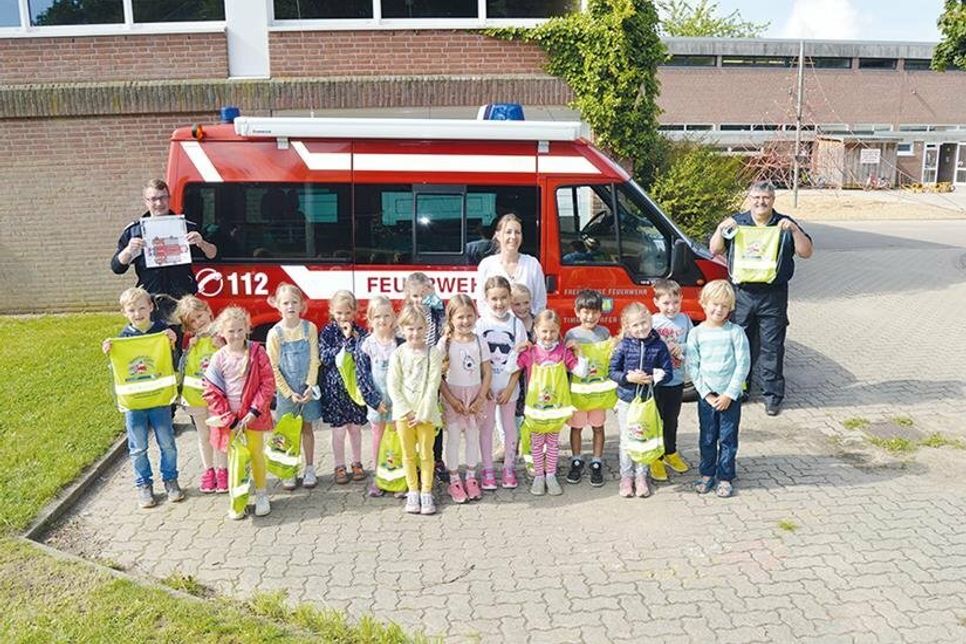 Stolz zeigen die Niendorfer Erstklässler mit Klassenlehrerin Aniela Weigel ihre hell leuchtenden, prall gefüllten Turnbeutel.