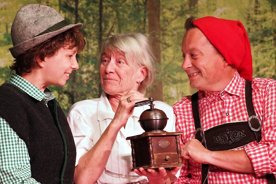 Die Großmutter (Sylvia Glismann) freut sich über die Kaffeemühle, die Seppel (Marcia Talleur, l.) und Kasperl (Marc Wiens) ihr geschenkt haben.