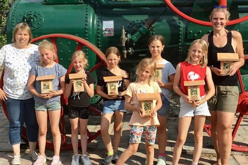 Ein Teil der Kinder präsentiert stolz die selbst gebauten Insektenhotels. Über die Aktion freuen sich natürlich die Ortsvereinsvorsitzende Angela Hüttmann (lks.) und Cathleen Dorl (re.), die den Nachmittag mit betreut hat. (Foto: Angela Hüttmann)