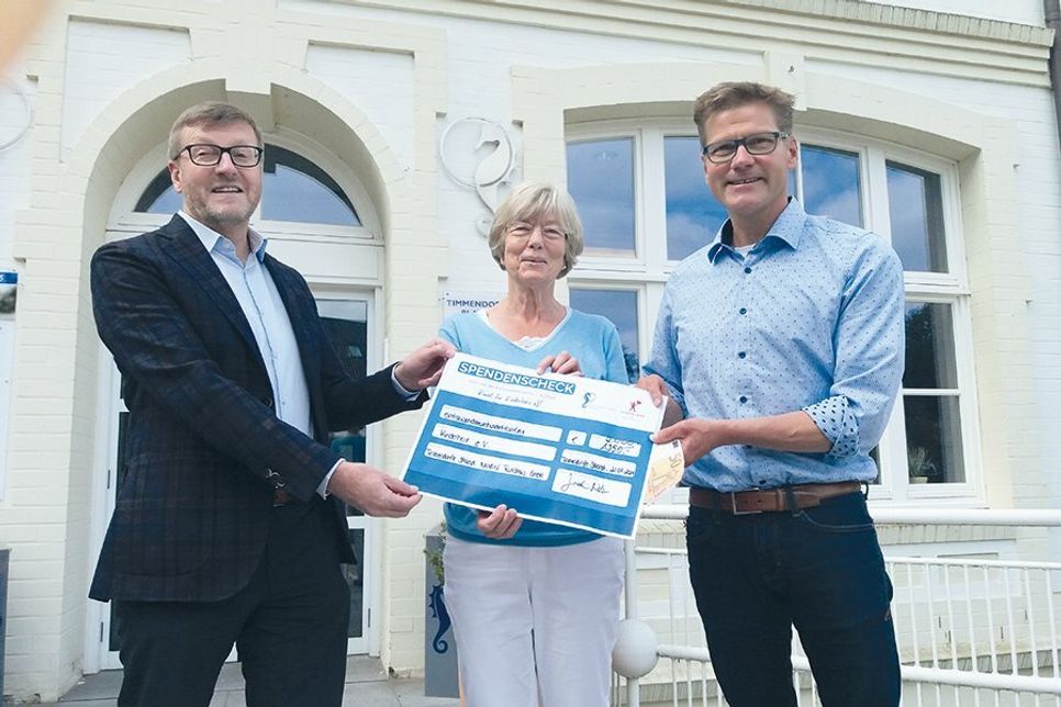 Timmendorfs Bürgermeister Sven Partheil-Böhnke (l.) und Tourismuschef Joachim Nitz übergeben den Spendenscheck an Barbara Bergmann, Vorsitzende des Vereins Kinderherz e.V..