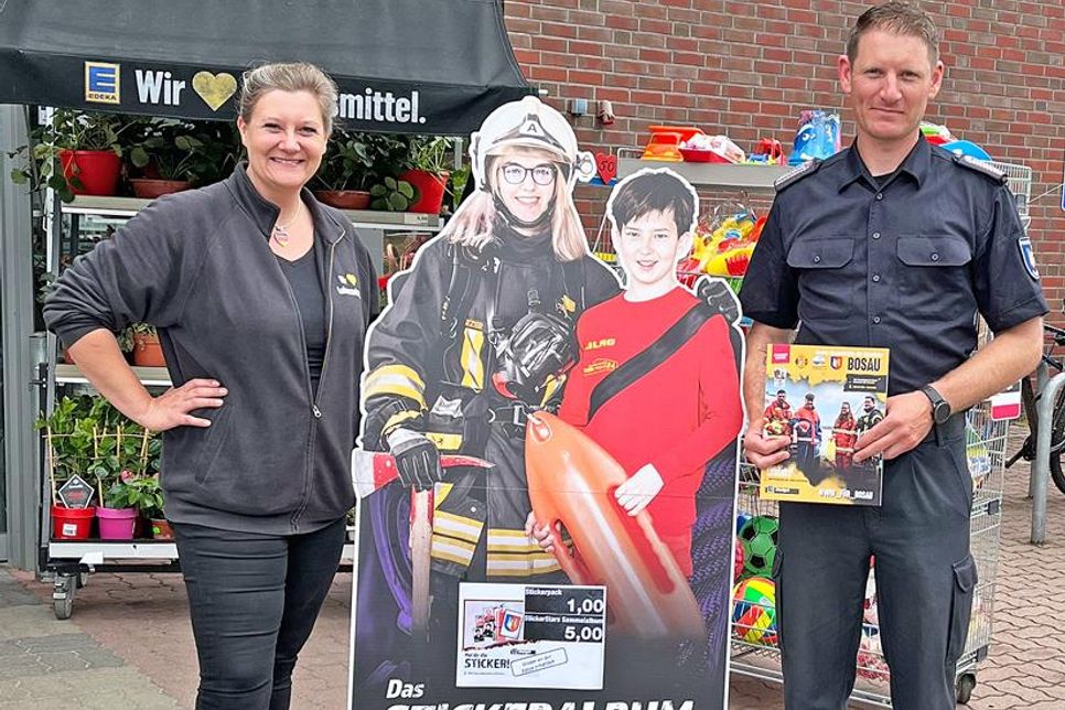 Julia Voigt vom Edeka Markt In Hutzfeld und der stellvertretende Gemeindewehrführer Andre Riemke präsentieren das Stickeralbum.