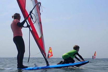 Spaß auf dem Board: Einfach mal vorne auf dem Surfbrett von der Surflehrerin über das Wasser fahren lassen.