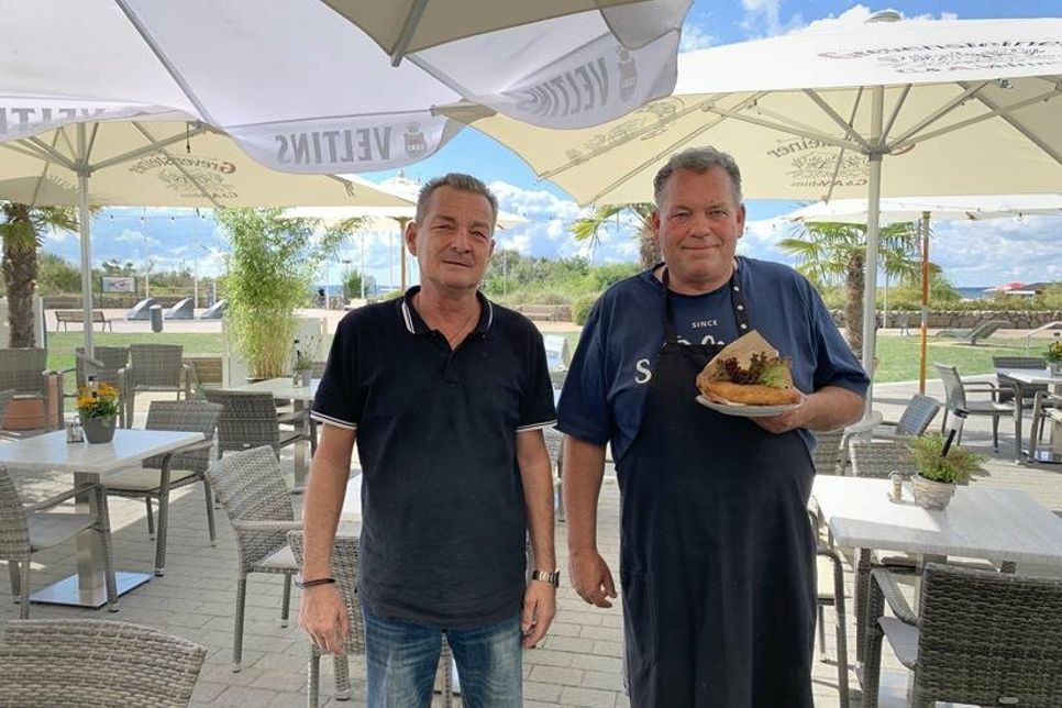 Thomas Nissen und Ulfert Georgs (re.) auf der Sonnenterrasse ihres Strandbistros am Seebrückenvorplatz.