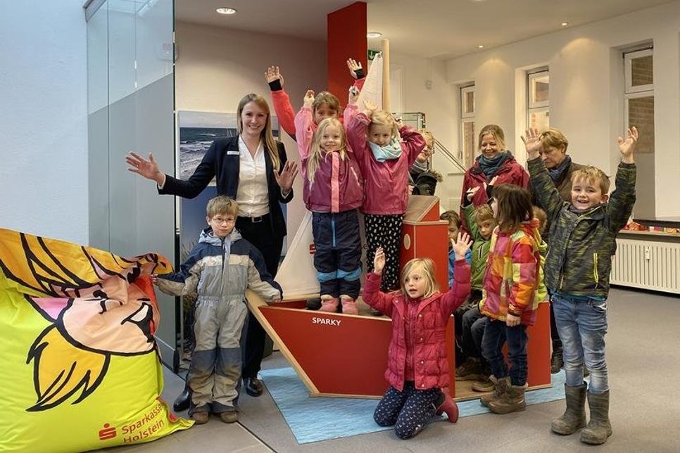 Jasmin Path (hi. lks.), Leiterin der Sparkasse-Holstein-Filiale in Lensahn, und Regina Kohlsaat (hi. re.), Leiterin des Kindergartens, sowie deren Mitarbeiterinnen mit ihren „Zwergen“ freuen sich über die Taufe des Knax-Bootes auf den Namen „Sparky“, mit dem die Kinder den großen Namenswettbewerb gewonnen hatten.