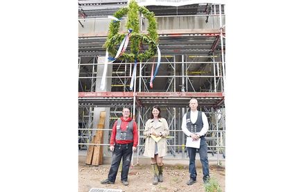 Betonbauer Thomas Klockmann (von links), Bürgermeisterin Bettina Schäfer und Polier René Zander nach dem Richtspruch unter dem Richtkranz, der jetzt über den Rohbau weht.