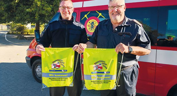 Gemeindejugendfeuerwehrwart Mirco Babin und Gemeindewehrführer Thomas Scharbau mit den Sportbeuteln, die sie kostenlos an die Erstklässler verteilt haben.