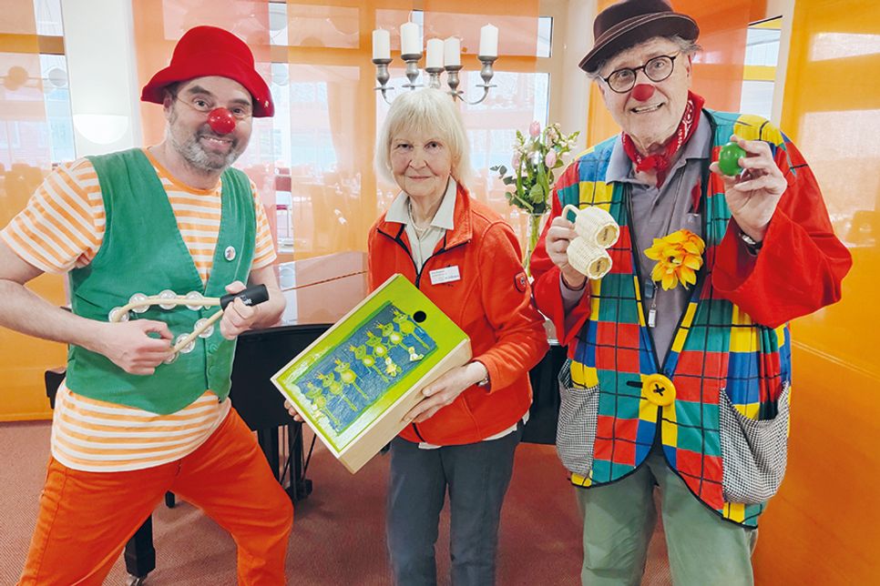 Die beiden Klinik-Clowns Holger „Schlenzo“ Stüve (links) und Gerhard „Flummi“ Flassak freuen sich über das Extra-Geschenk aus den Händen von Erika Weigandt.