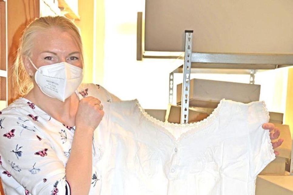 Museumsleiterin Julia Meyer präsentiert ein Leinenunterkleid oder -nachthemd als Teil einer Aussteuer Anfang des 20. Jahrhunderts.