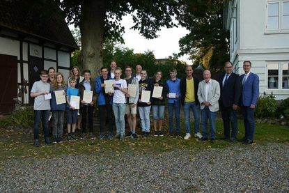 Das Foto zeigt die stolzen Preisträger mit ihren Urkunden, der Schulleitung, Karsten Kilian und Ralf Hübner, den betreuenden Lehrerinnen Nadja Schömig und Judith Schidlo, den Vertretern der Stadt Neustadt, Bürgermeister Mirko Spiekermann, Bürgervorsteher Sönke Sela) und vom Rotary Club Neustadt-Ostsee Präsident Axel Sommerlatt sowie MINT-Projektleiter Georg Heerten im Bereich der Hofanlage Marienhof.