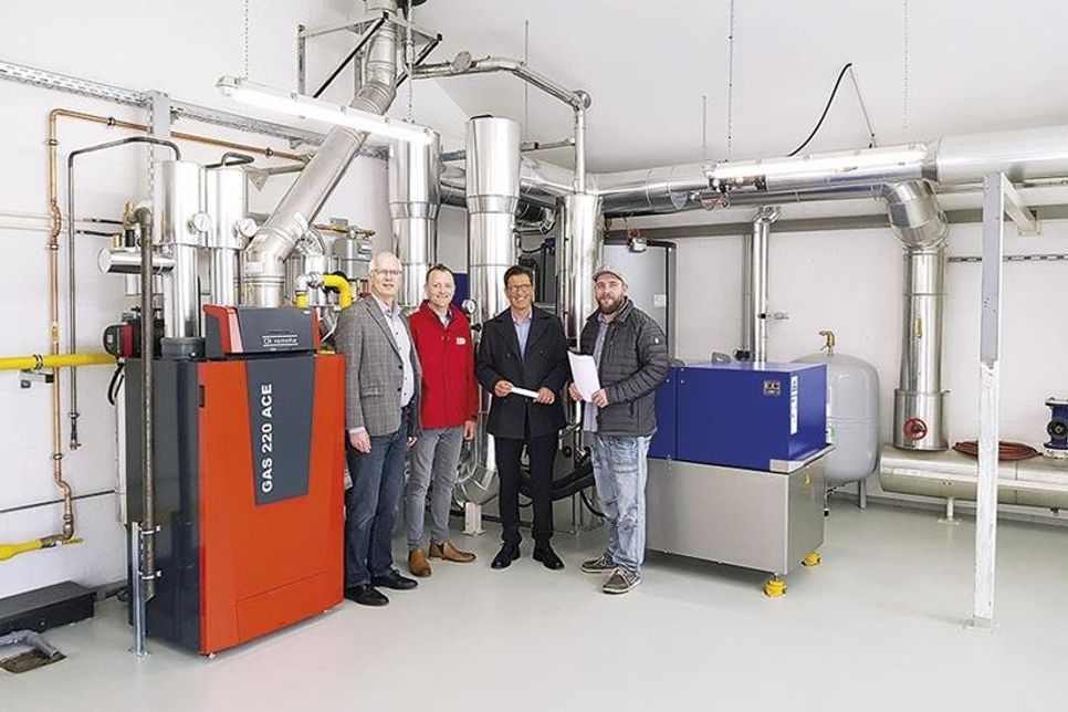 Zusammen mit Ratekaus Klimamanager Alexander Herberger (v.r.) und Bürgermeister Thomas Keller nahmen Jost Glüsing und Rüdiger Lange-Jost von der ZVO Energie GmbH die neue Wärmeanlage in Techau in regulären Betrieb. Die linke, rote Anlage ist der Gasbrennwertkessel und rechts in blau ist das Blockheizkraftwerk zu sehen. (Foto: ZVO/hfr)