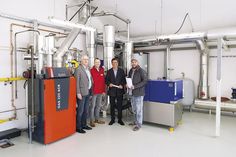 Zusammen mit Ratekaus Klimamanager Alexander Herberger (v.r.) und Bürgermeister Thomas Keller nahmen Jost Glüsing und Rüdiger Lange-Jost von der ZVO Energie GmbH die neue Wärmeanlage in Techau in regulären Betrieb. Die linke, rote Anlage ist der Gasbrennwertkessel und rechts in blau ist das Blockheizkraftwerk zu sehen. (Foto: ZVO/hfr)