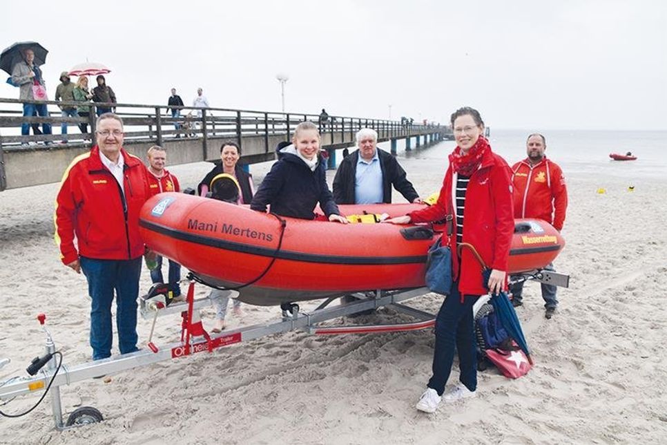 DLRG-Fundraising-Leiter Achim Wiese (von links), der Technische Leiter Marcel Howanietz, die Scharbeutzer Bürgermeisterin Bettina Schäfer, DLRG-Kuratoriumsmitglied Hans Meiser und Abschnittsleiter Peter Franz mit Taufpatin Verena Mertens (vorne) und Tochter Elisabeth, die im neuen Rettungsboot, das ihr Opa gespendet hat, Platz genommen hat.