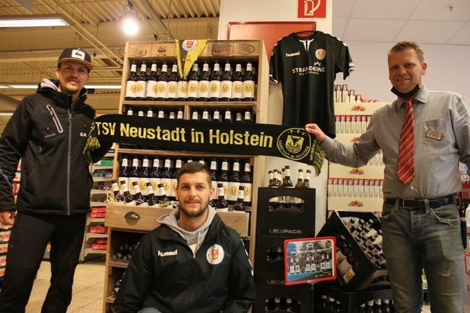TSV-Initiator Sascha Herz, Fußball-Abteilungsleiter Jan-Hendrik Malzkeit und famila-Warenhausleiter Mathias Affeldt (v. lks.) präsentieren die Biersorte, die in einem Sonderaufbau im Eingangsbereich des Marktes erhältlich ist.