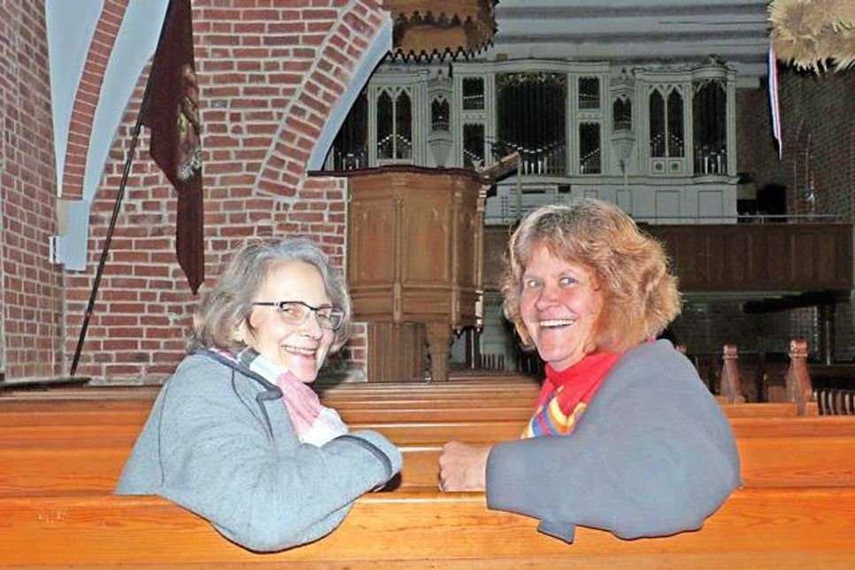 Die beiden Ahrensböker Pastorinnen Christine Grossmann und Kirstin Mewes-Goeze auf den Kirchenbänken, die mit dem Rücken zum Altar stehen.