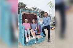 Hannah Block (links) und Lea Muuß aus der Marketingabteilung der TSNT GmbH und Tourismuschef Joachim Nitz mit dem umgestalteten Strandkorb, der jetzt als Fotomotiv für das Gewinnspiel am Timmendorfer Sportstrand platziert wurde.