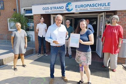 Björn Bernitt (Firma nora systems GmbH) übergibt das Zertifikat an Melanie Puschaddel-Freitag, 1. stellv. Bürgermeisterin der Gemeinde Timmendorfer Strand. Mit ihnen freuen sich über die erfolgreiche Sanierungsmaßnahme Ester Passig (v.l.), Schulleiterin der Grund- und Gemeinschaftsschule Timmendorfer Strand, Christoph und August-Dietrich Schult (Architekten), Andreas Christiansen (Projektsteuerung) und Bauamtsleiterin Christina Bonke.