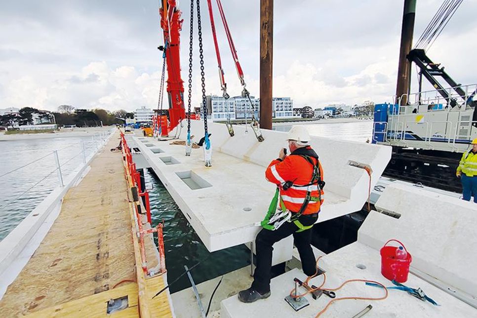 Mit einem 700-Tonnen-Mobilkran werden die Balkonteile millimetergenau in den Neubau der Scharbeutzer Seebrücke eingesetzt.