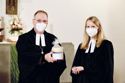 Propst Peter Barz überreicht Pastorin Inga Schwerdtfeger eine der großen „Outdoor-Kerzen“, die alle neuen Mitarbeiterinnen und Mitarbeiter im Kirchenkreis erhalten.