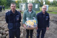 Für seine Spende bedankten sich Frank Paustian (re.) und Jan Reiche (lks.) mit einem Präsentkorb bei Hinrich Behrens. Im Hintergrund die beiden Container.