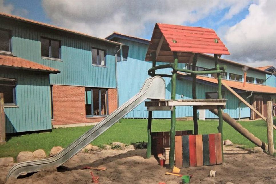 Auch die blauen Häuser sind 2000 entstanden und zeigen links den heutigen Hort und rechts die Turnhalle, die sich im großen Verwaltungsgebäude befindet.