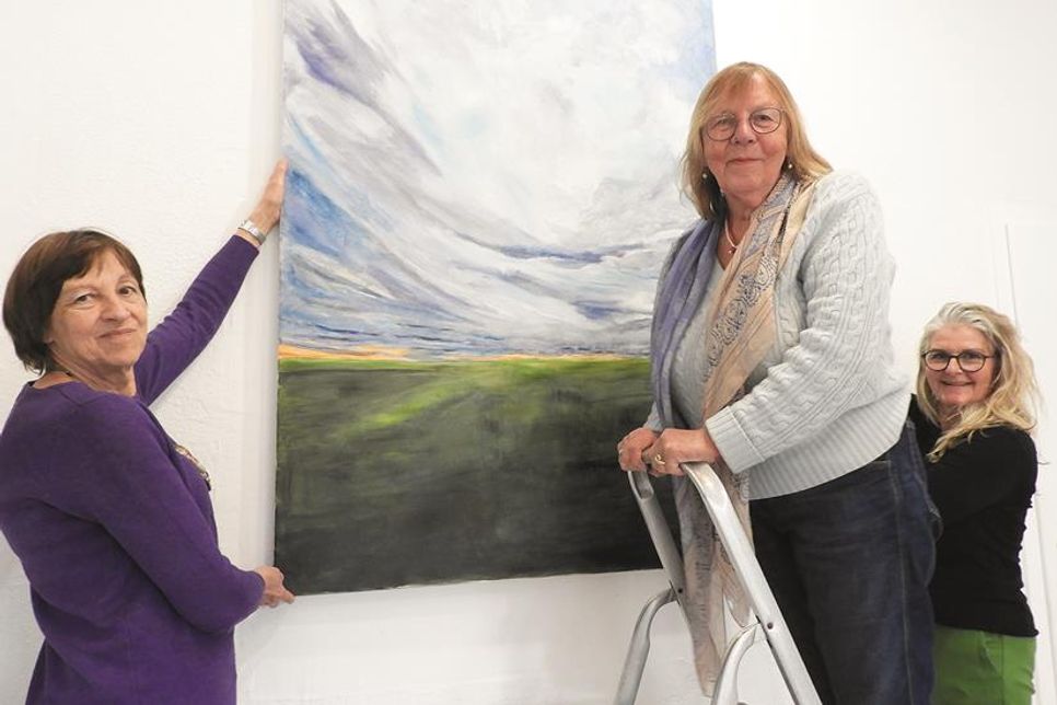 Ein guter Platz für schöne Bilder: Dr. Ilse Heberlein (Vorsitzende Kunstkreis), Angela Warnecke-Trabandt und Martina Baumgardt (Kunstraum 36) hängen ein Werk von Christian Trabandt auf.