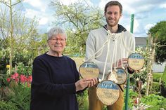 Karin Paprzik, Atelier Grell, und Sebastian Welte, Klimaschutzmanager der Stadt Plön, werben um Einsendungen im Rahmen des Klimaschutzwettbewerbs 2024 – die selbstgebauten und bemalten Medaillen aus Holz aus dem Garten geben ein Beispiel in Sachen Nachhaltigkeit ab