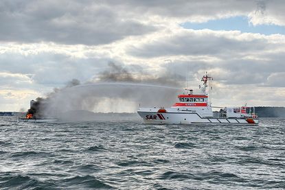 Der Seenotrettungskreuzer FELIX SAND der DGzRS bekämpft den Brand auf einer Segelyacht vor Travemünde.