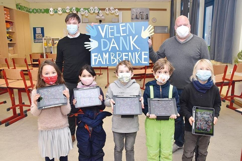 Amelie (von links), Sophia (beide 6), Liam, Richard und Mats (alle 7) aus der ersten Klasse bedanken sich stellvertretend für alle Schulkinder bei Familie Brenke für die großzügige Spende. Auch Hauptamtsleiter Dennis Sontopski (links) und Schulleiter Stephan Wiese freuen sich über die Anschaffung der iPads.