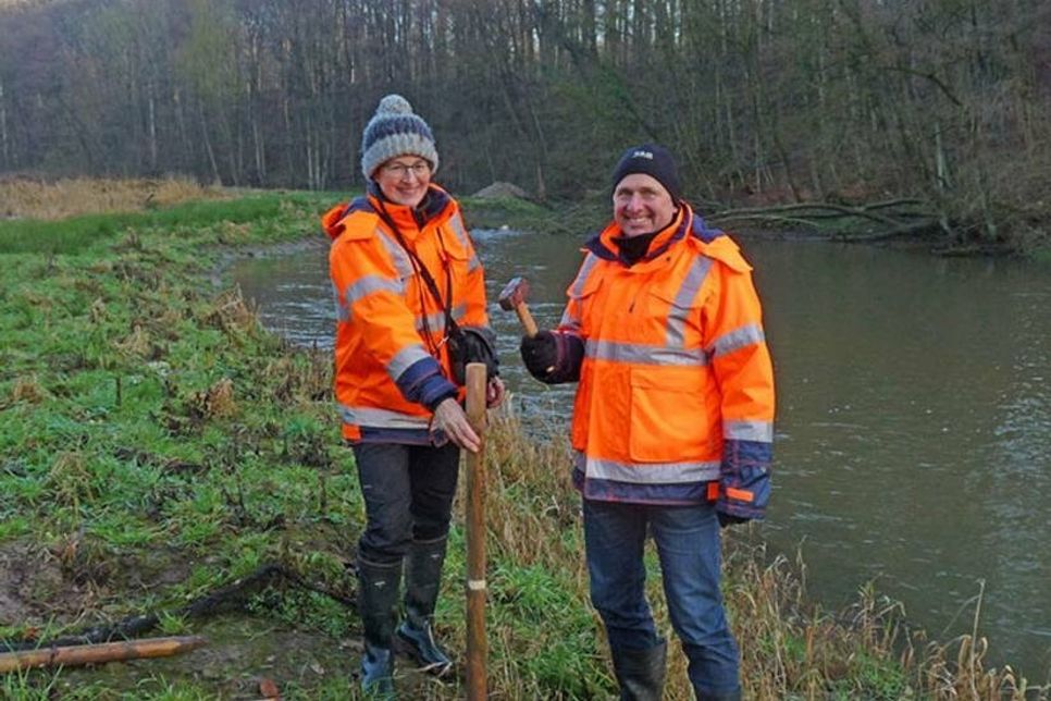 Hanna Kirschnick-Schmidt und Jörg Sommerfeld schlagen an einem renaturierten Abschnitt der Schwartau südlich von Hobbersdorf symbolisch den Pflock für weiterhin naturnahe Verbandsgewässer ein.
