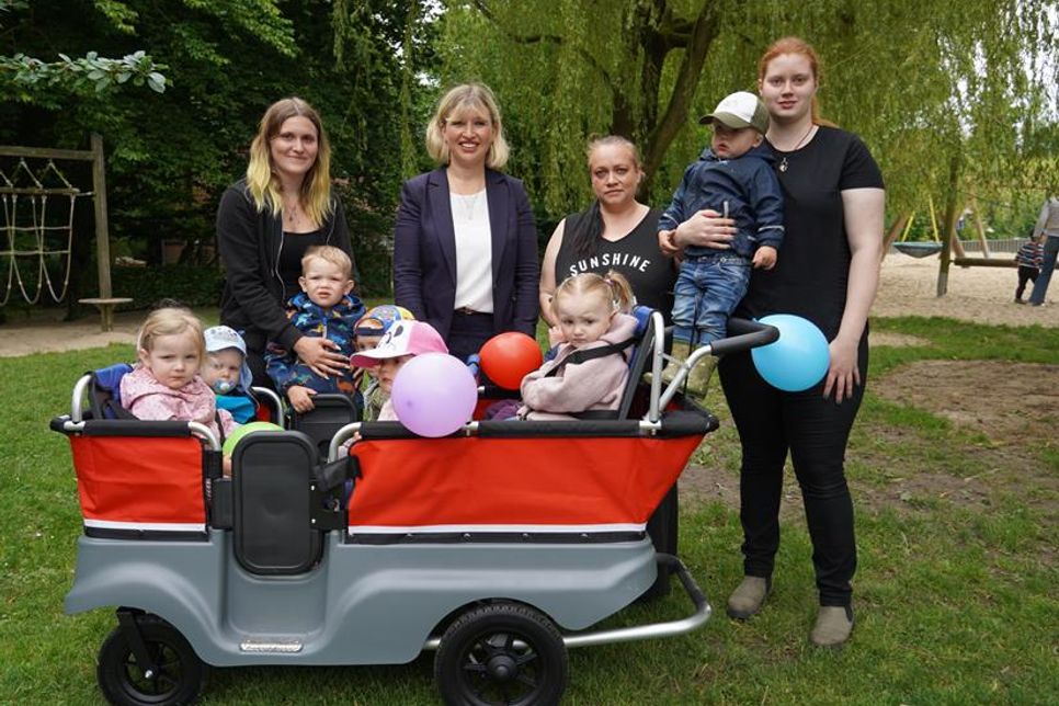 Übergabe des Krippenbusses mit Kindergartenleiterin Peggy Sumpf-Gies (2. v. re.) Janina Oldenkop-Timm von der Sparkasse Holstein sowie Erzieherinnen und Krippenkindern.