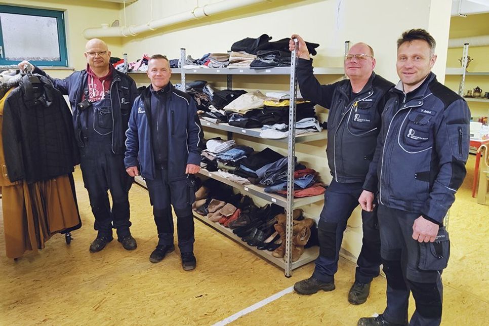 Die Mitarbeiter des Bauhofs vor einem der vielen neuen Schwerlastregalen, die mit Kleidungsstücken gefüllt sind.