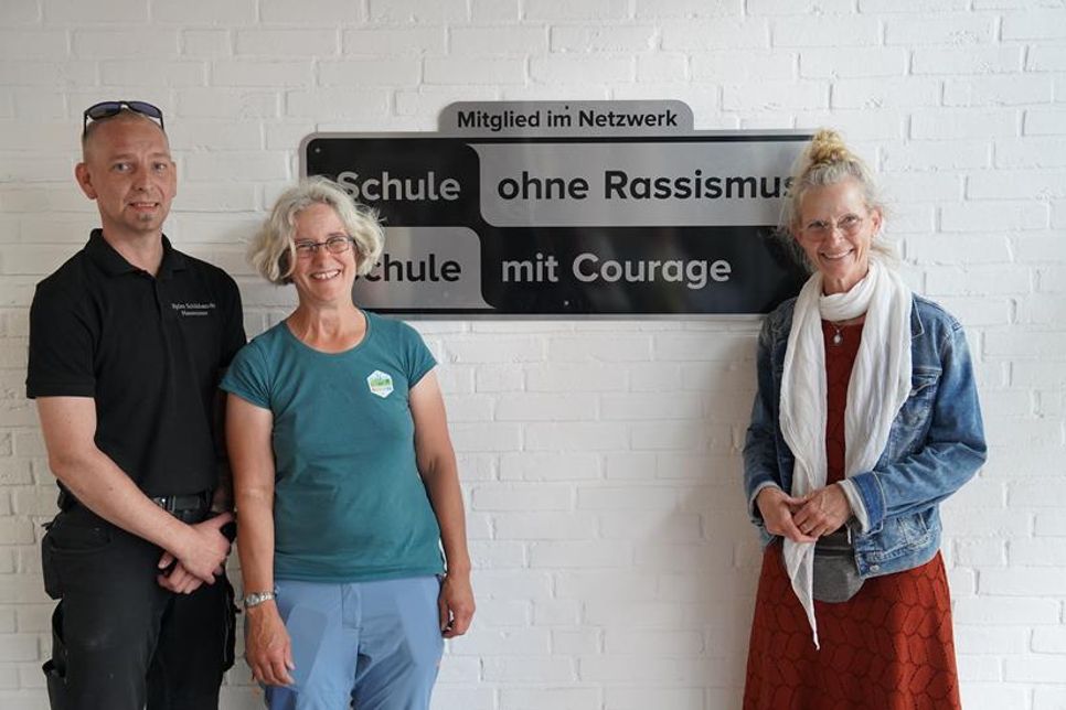 Das neue Schild wurde mit Hilfe von Hausmeister Björn Schildknecht direkt aufgehängt. Schulleiterin Doris Jürs (re.) und Birte Wolter von der Aktionsgruppe der Gemeinde freuten sich über die Auszeichnung.