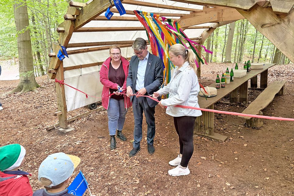 Mit dem Durchschneiden des Bandes gaben Maike Vogler vom Kinderschutzbund (links), Bürgermeister Heiko Godow und Kita-Leiterin Christine Erdmann den Waldplatz offiziell frei.