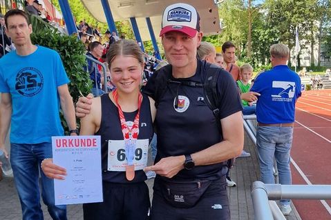 Pia Feline Loors nach der Siegerehrung mit Medaille neben ihrem Heimtrainer Andreas Boller.