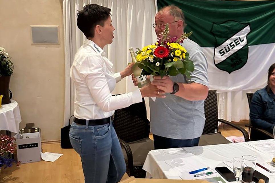 Jessica Mühlenberg überreicht Martin Rothenbüchler Sekt und Blumen zur Wiederwahl des 2. Vorsitzenden.