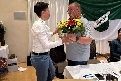 Jessica Mühlenberg überreicht Martin Rothenbüchler Sekt und Blumen zur Wiederwahl des 2. Vorsitzenden.