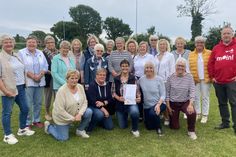 Sparkassen-Filialleiter Fabian Wierichs (re.) und 2. KSV-Vorsitzende Jutta Voigt (stehend 6. von re.) überraschten Marina Bütje (knieend Mitte) gemeinsam mit der DSG. (Foto: Carsten Stender, Kreissportverband Ostholstein)