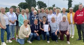Sparkassen-Filialleiter Fabian Wierichs (re.) und 2. KSV-Vorsitzende Jutta Voigt (stehend 6. von re.) überraschten Marina Bütje (knieend Mitte) gemeinsam mit der DSG. (Foto: Carsten Stender, Kreissportverband Ostholstein)