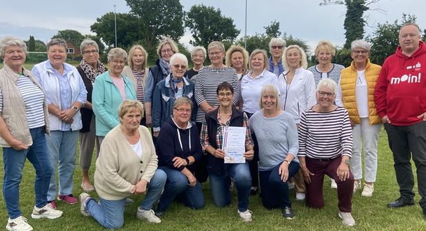 Sparkassen-Filialleiter Fabian Wierichs (re.) und 2. KSV-Vorsitzende Jutta Voigt (stehend 6. von re.) überraschten Marina Bütje (knieend Mitte) gemeinsam mit der DSG. (Foto: Carsten Stender, Kreissportverband Ostholstein)