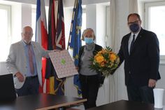 Blumen und eine Collage von Neustadt-Bildern gab es zum Abschied für Gisela Künkel von Bürgervorsteher Sönke Sela und Bürgermeister Mirko Spieckermann (re.).