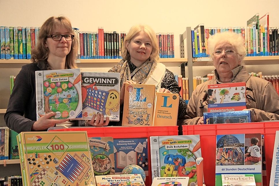 Sabine Stryga, Larisa Sharapova und die ehrenamtlich tätigen Sprachlehrerin Barbara Hillmann (v. lks.) präsentierten in der Stadtbücherei die Medienauswahl für Migranten.